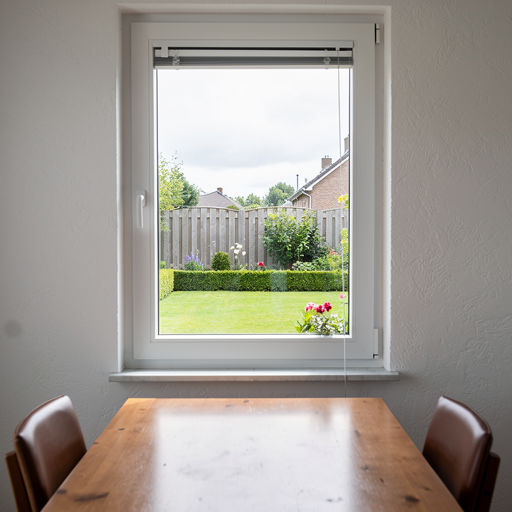 uitzicht vanuit eetkamer in Vlijmen door wit kunststof draai-kiepraam naar achtertuin